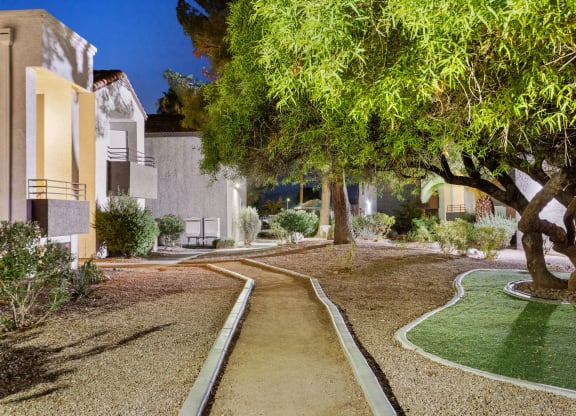 a pathway through a yard with trees and buildings in the background